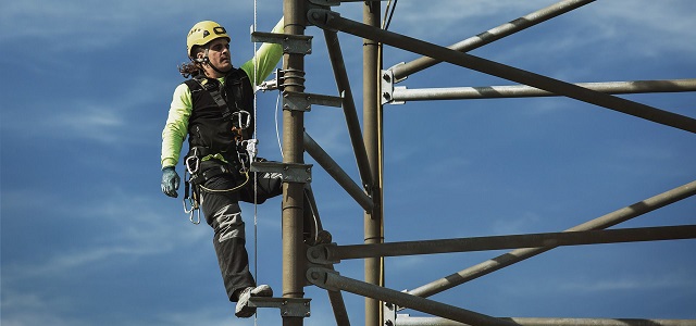 Seorang pekerja sedang bekerja di atap gedung dengan menggunakan produk safety lifeline dari Fallprotec